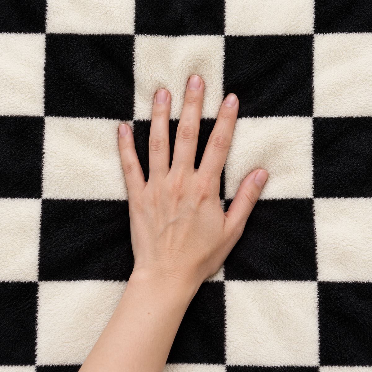Amelvi black soft throw blanket pressed by an adult hand on its short plush checkerboard face