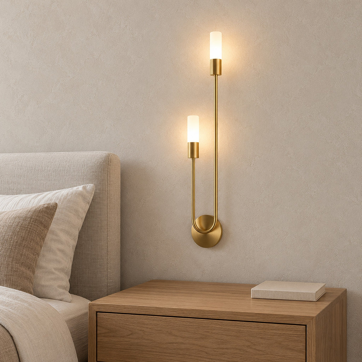 Amolven gold wall light detail of the circular wall plate against clean plaster with both heads switched on