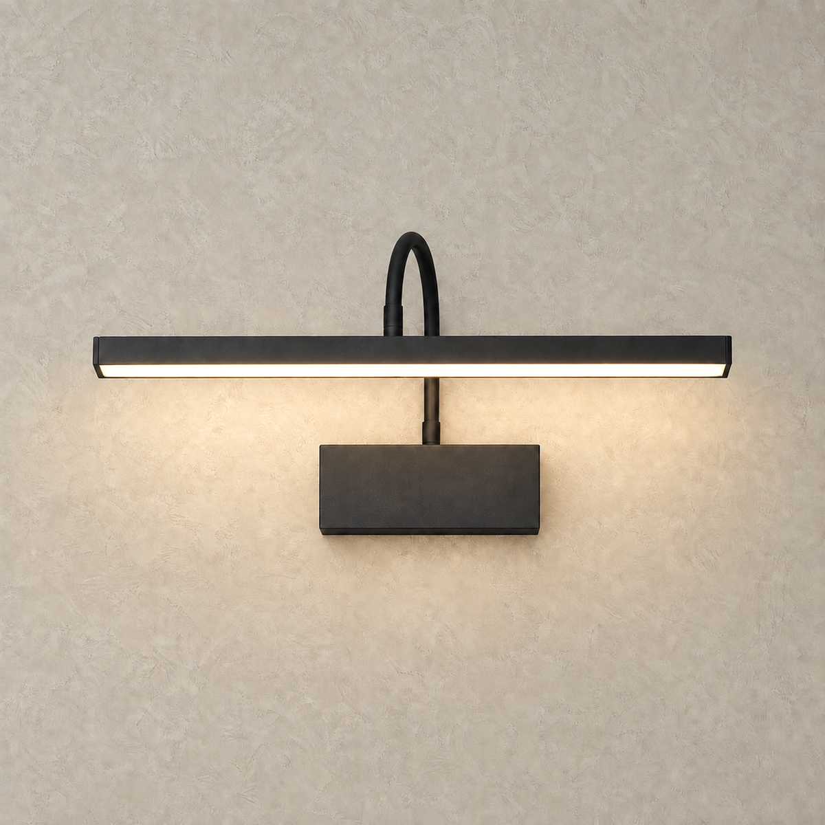 Anvelio black LED wall sconce lit and glowing against warm greige plaster