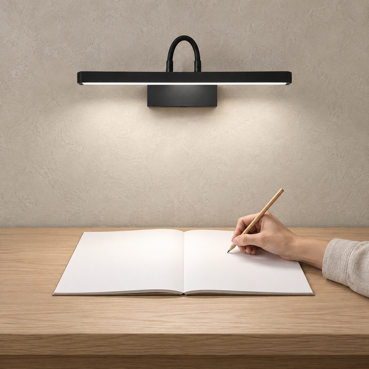 Anvelio black wireless wall light over an open notebook and a writing hand at a daylit desk