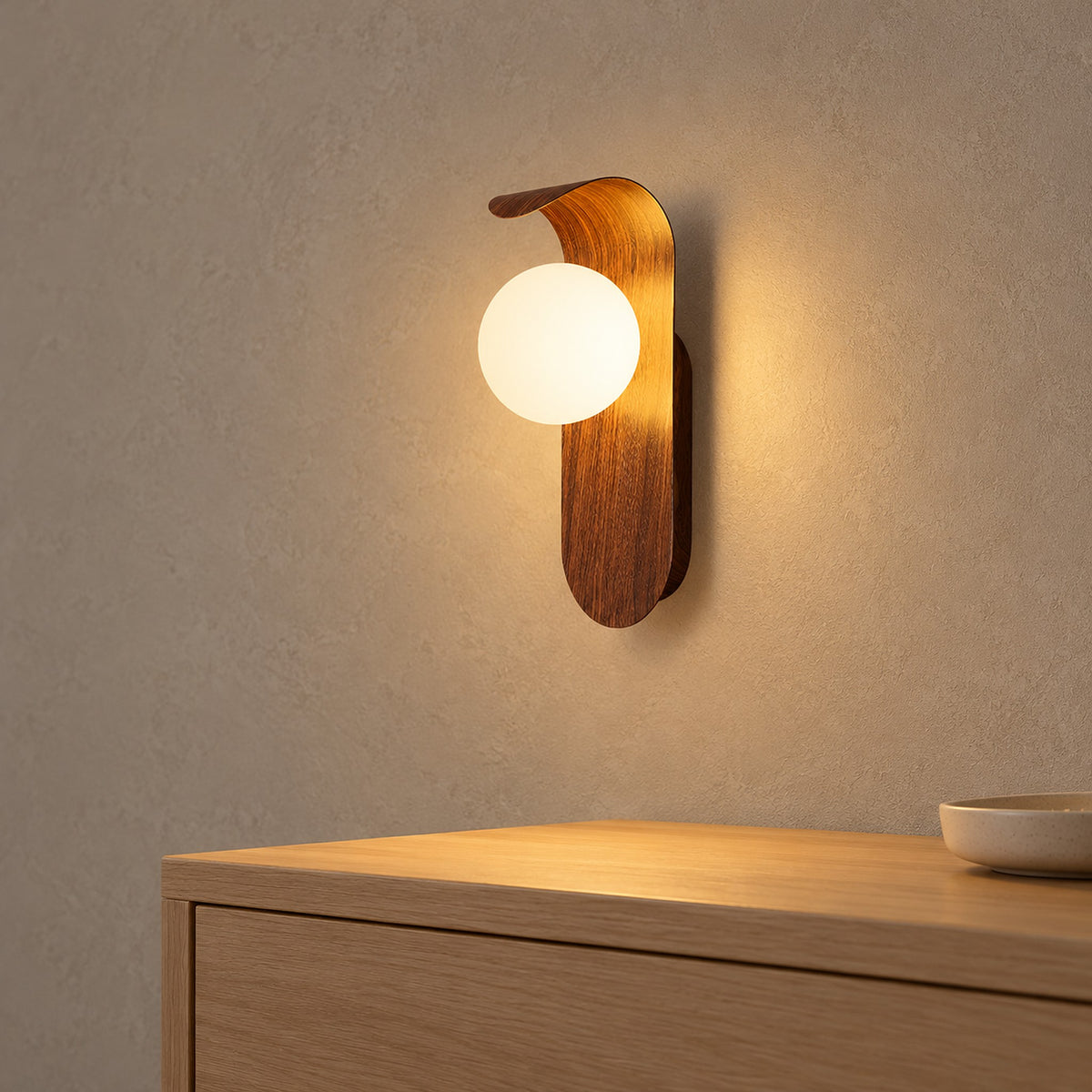 Arcelmo walnut wall lamp detail with the glowing globe lighting the curved wood grain accent above it