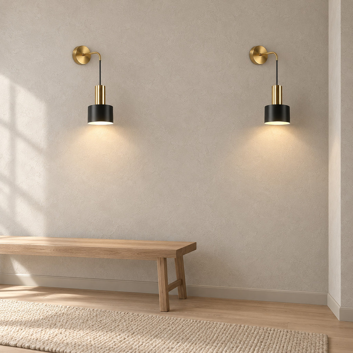 Arsomel black and gold wall light pair glowing on bare plaster in a daylit hallway