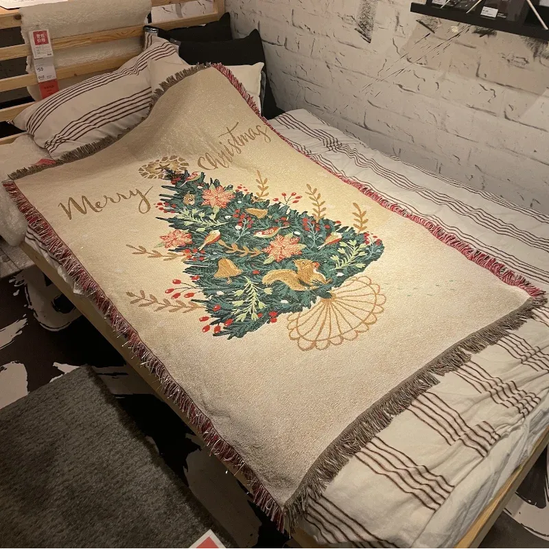 Canelvi christmas jacquard throw blanket spread on a bed, showing a Christmas tree design and fringed edges.