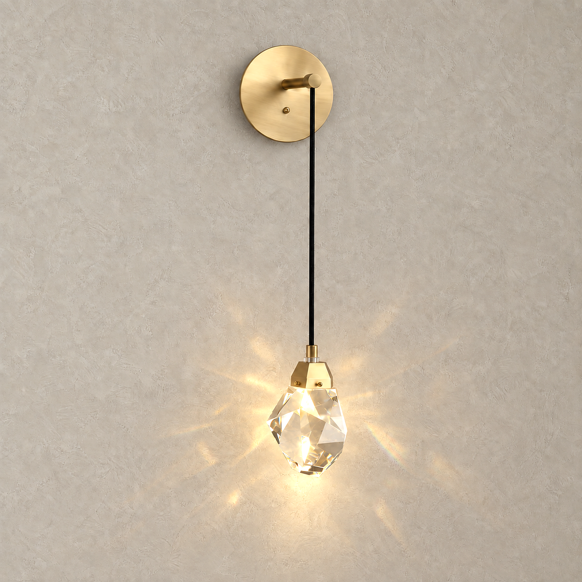 Caresilo brass color crystal wall lamp lit, casting angular warm light