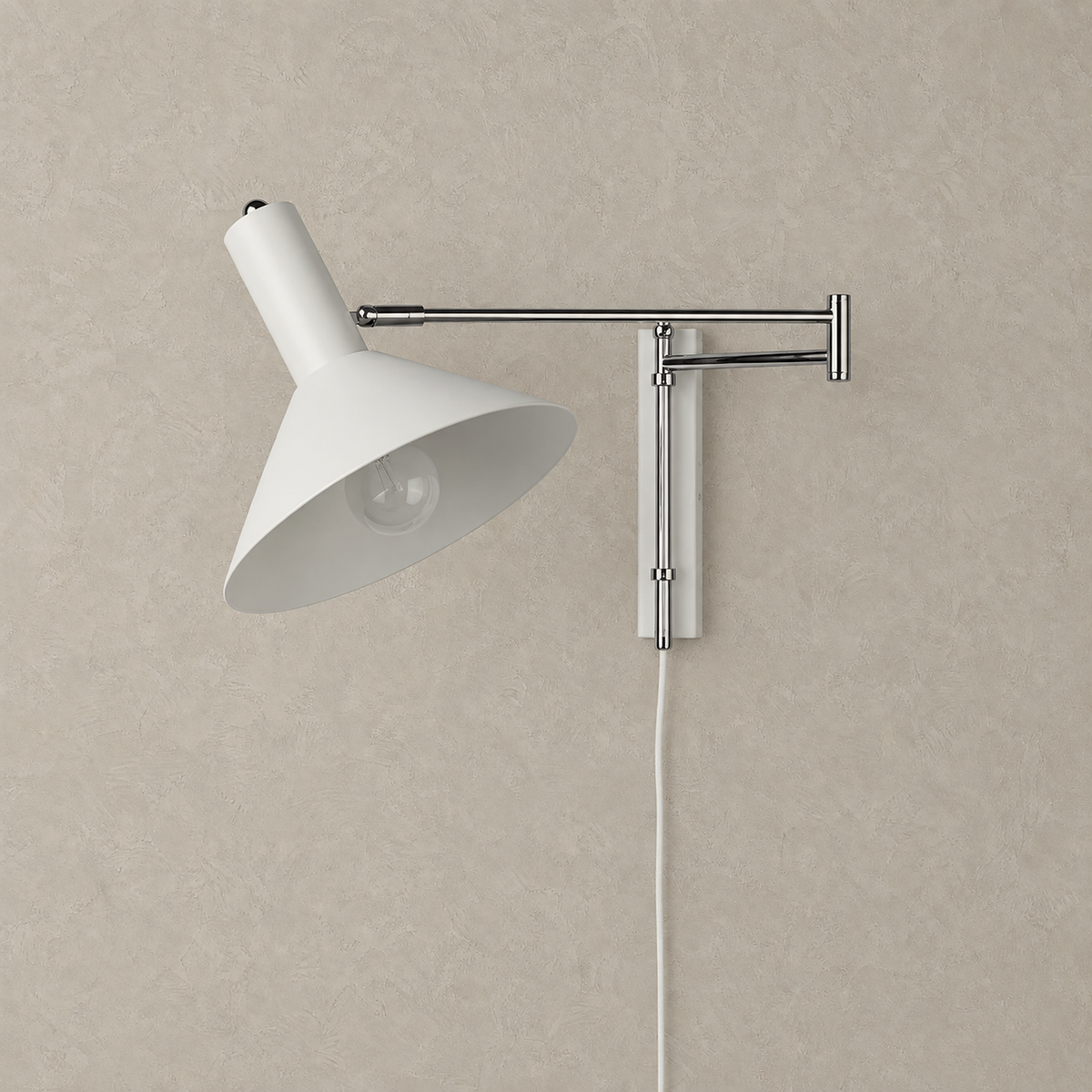 Celmoira white wall mounted bedside lamp with its broad metal cone and slim arms on a plain background