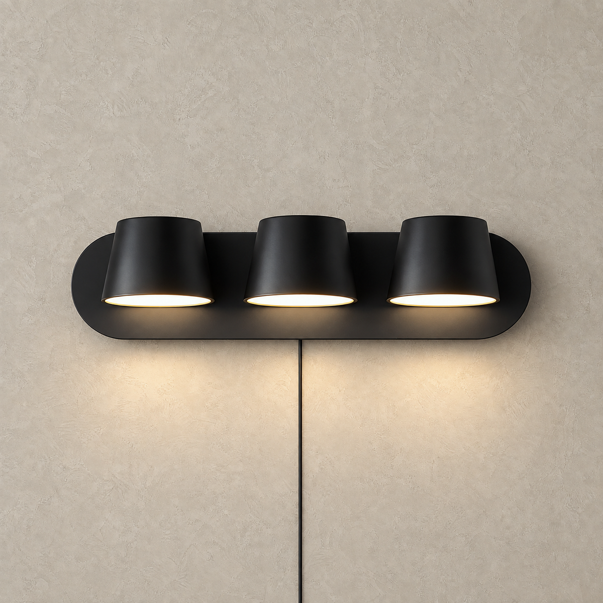 Cirelvo black three light bedside lamp lit with warm light on a plain studio plate