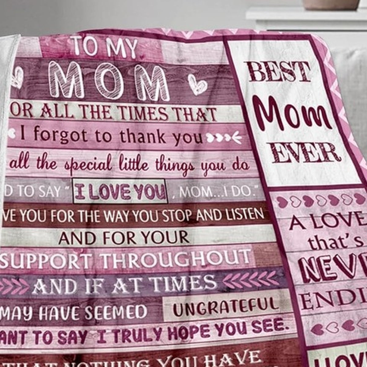 Elmisa mom fleece throw blanket draped over a sofa, showing pink and burgundy panels with hearts and messages to Mom.