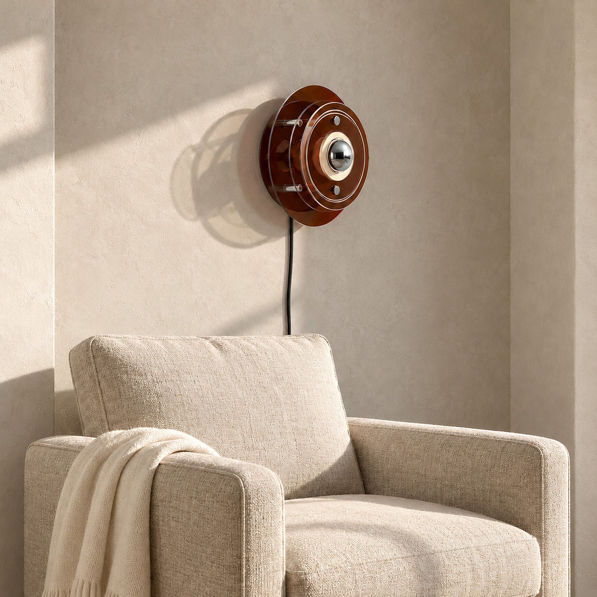 Elsarvo brown wall lamp unlit above an oatmeal armchair in a daylit alcove