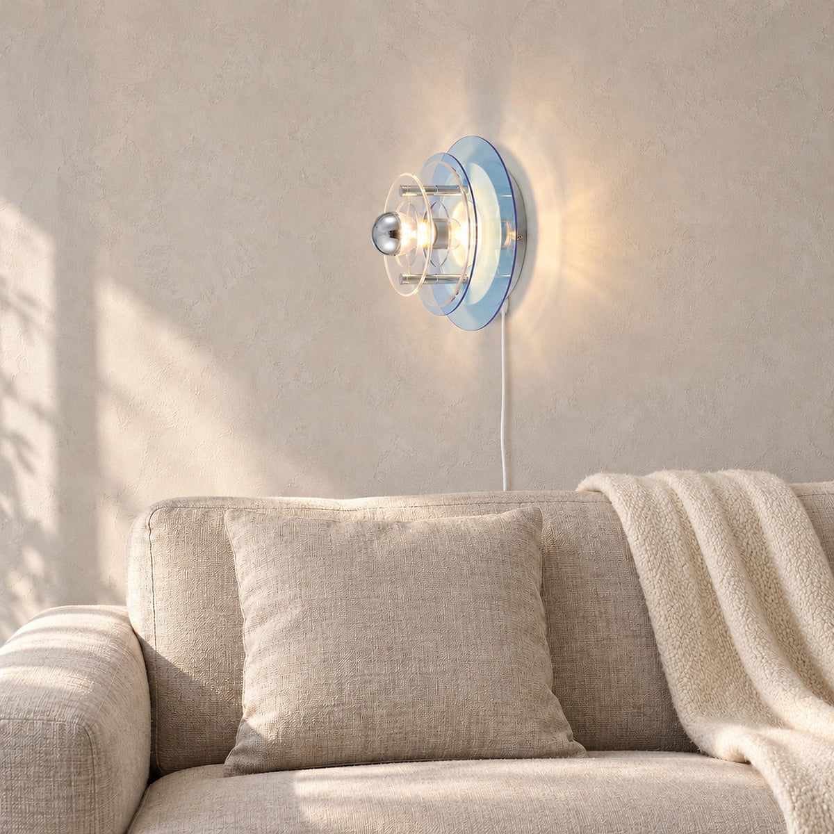 Elsarvo light blue plug in wall sconce lit above oatmeal snug seating #color_light blue