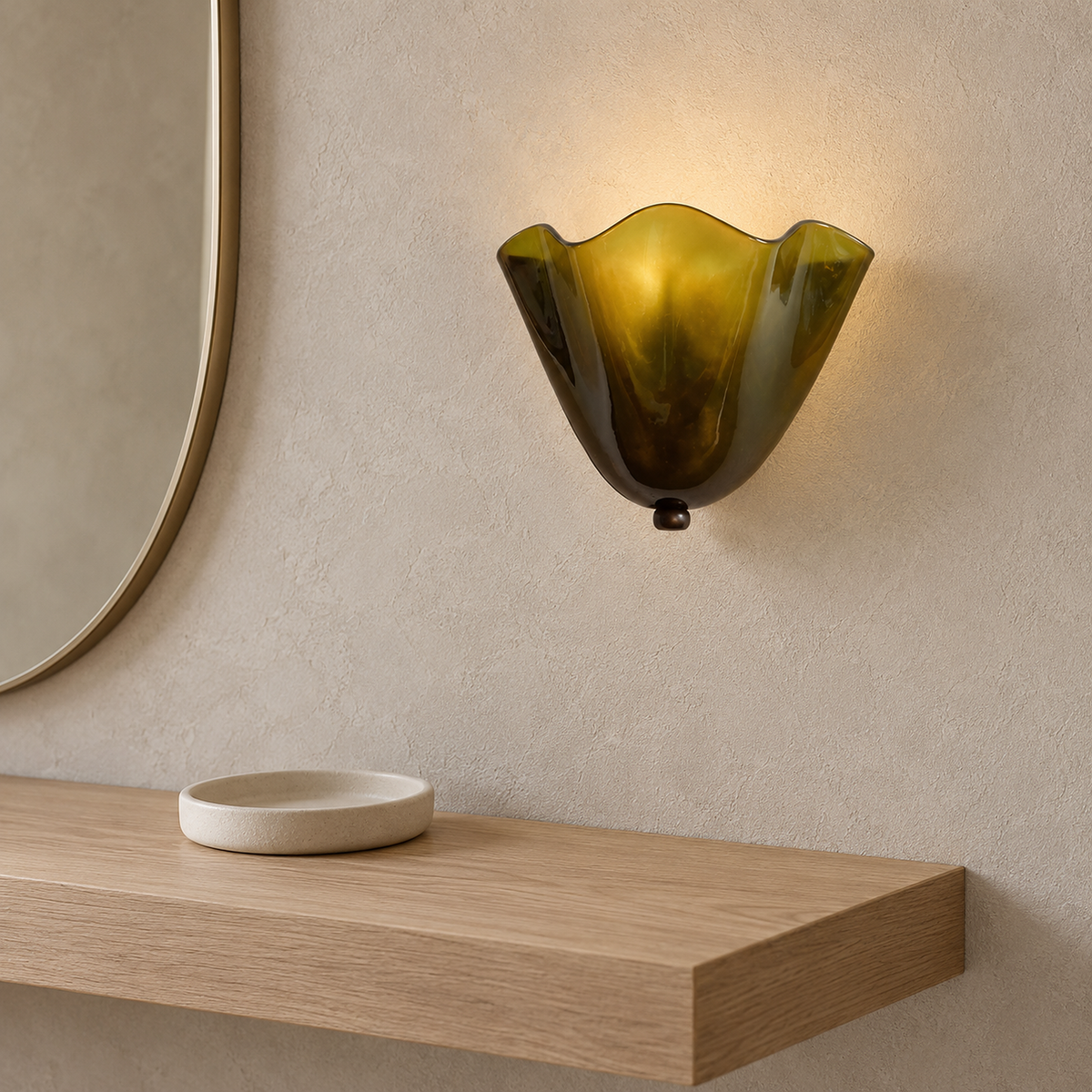 Ilsaren green wall sconce lit in a bedroom dressing corner, its folded glass seen from the side