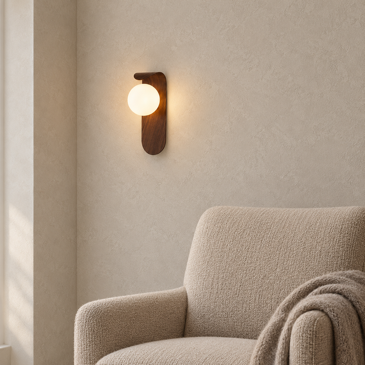 Ilvarne walnut wall lamp, warm globe glowing against the curled top of its curved panel
