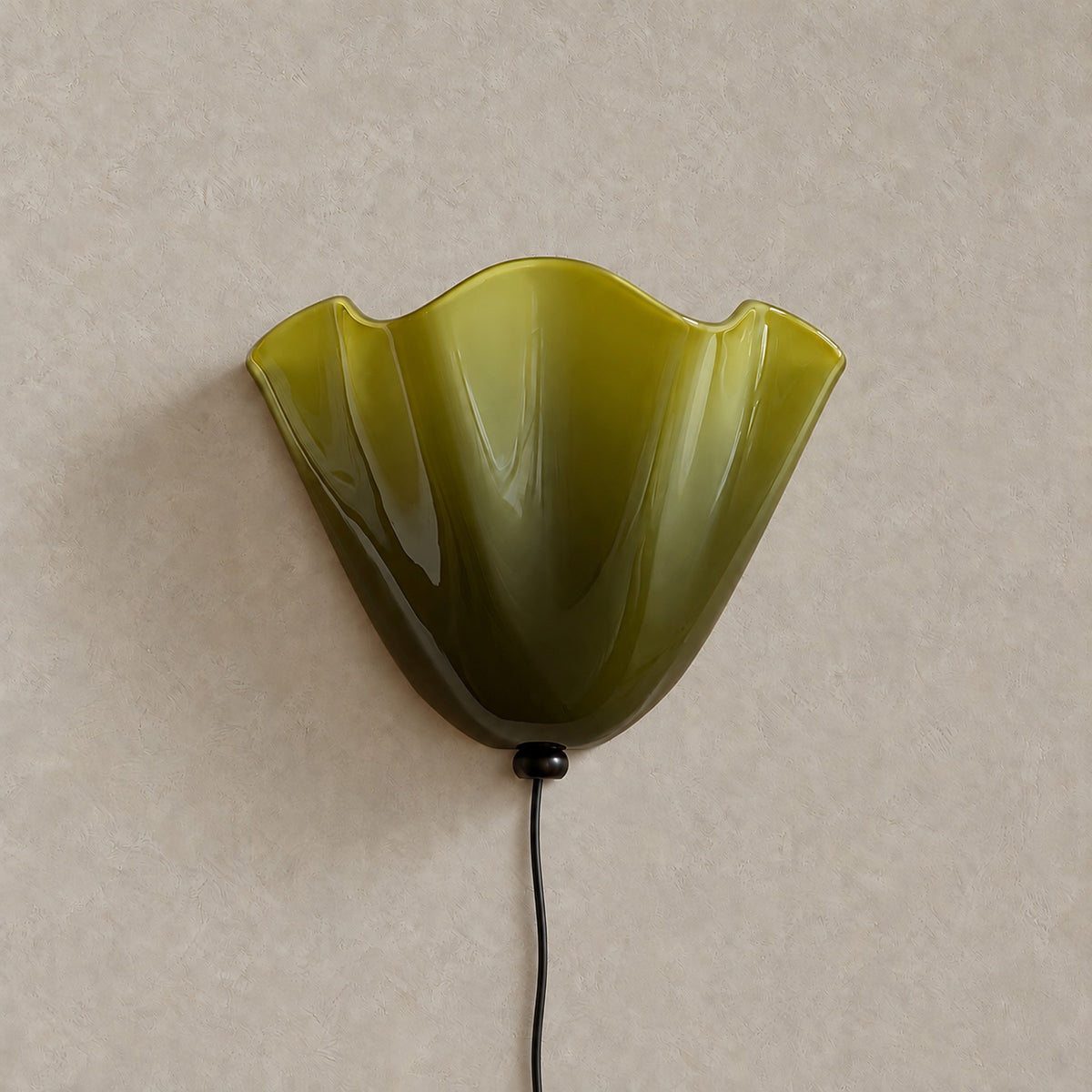 Lanorvi green glass bedside wall light, unlit against a greige plaster wall #color_green