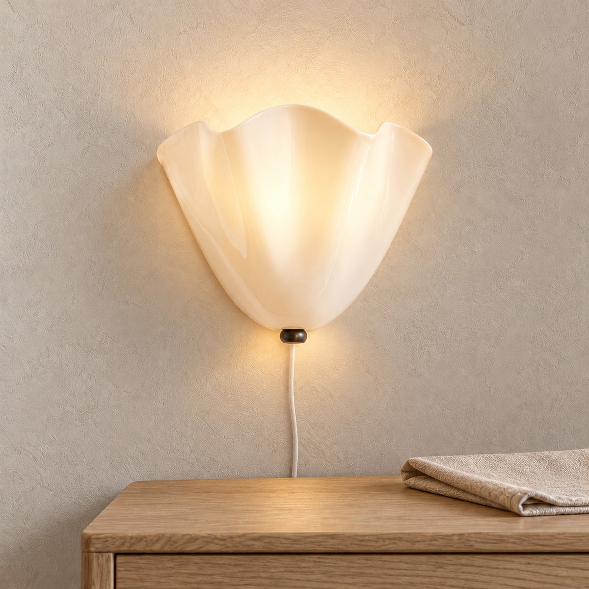 Lanorvi ivory glass wall lamp glowing above a dining room sideboard in daylight