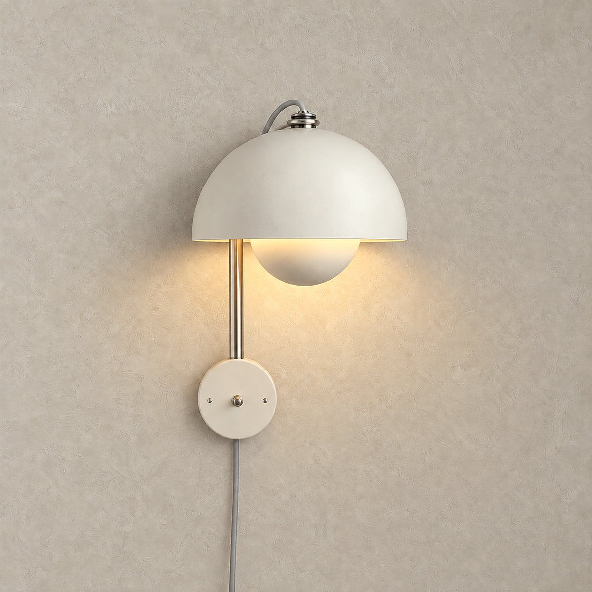 Lasorme cream bedside wall light lit against warm greige plaster, its dome shade glowing softly