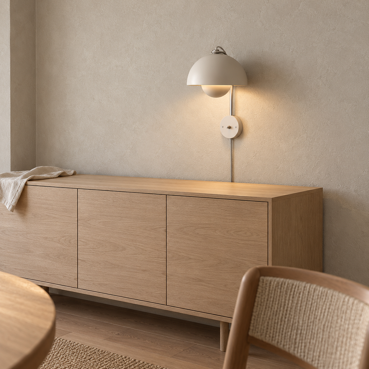 Lasorme cream wall light lit above a dining sideboard in daylight