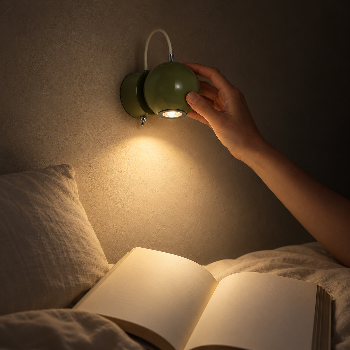 Lirema green LED wall sconce angled to aim warm light across the open pages of a reader in bed