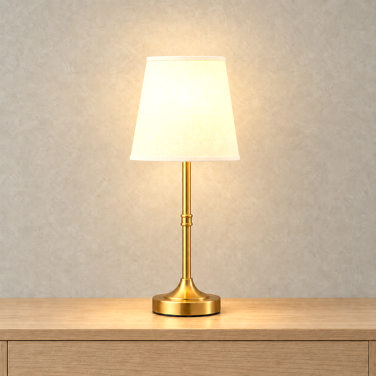 Lorvesa gold rechargeable table lamp switched on with its white woven shade lit from within