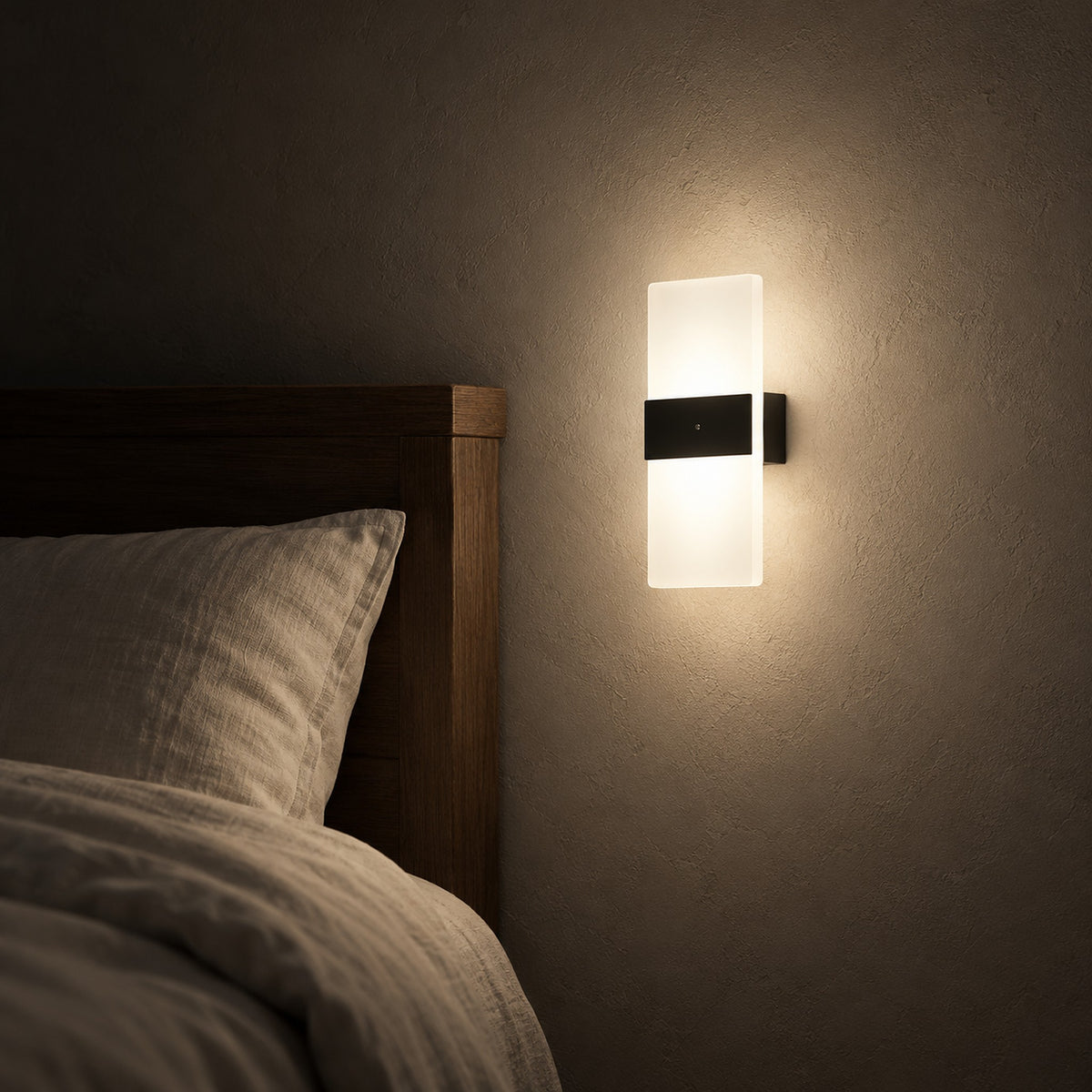 Melavor black battery operated wall sconce glowing beside a made bed at night