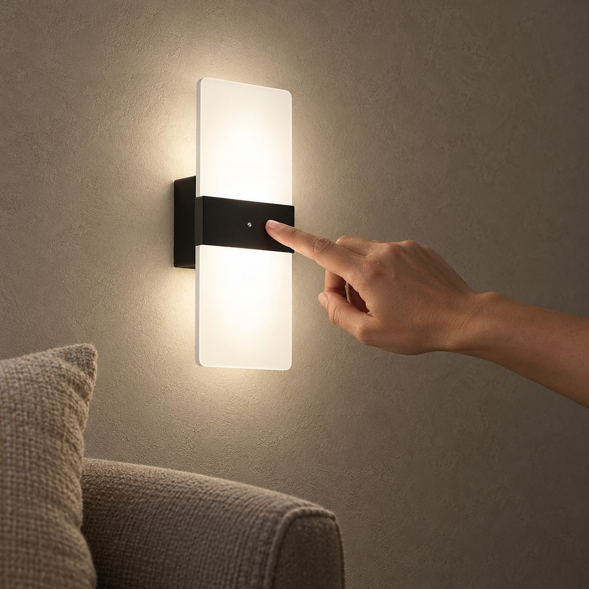 Melavor Black rechargeable wall sconce glowing beside an armchair, with a hand touching its central panel