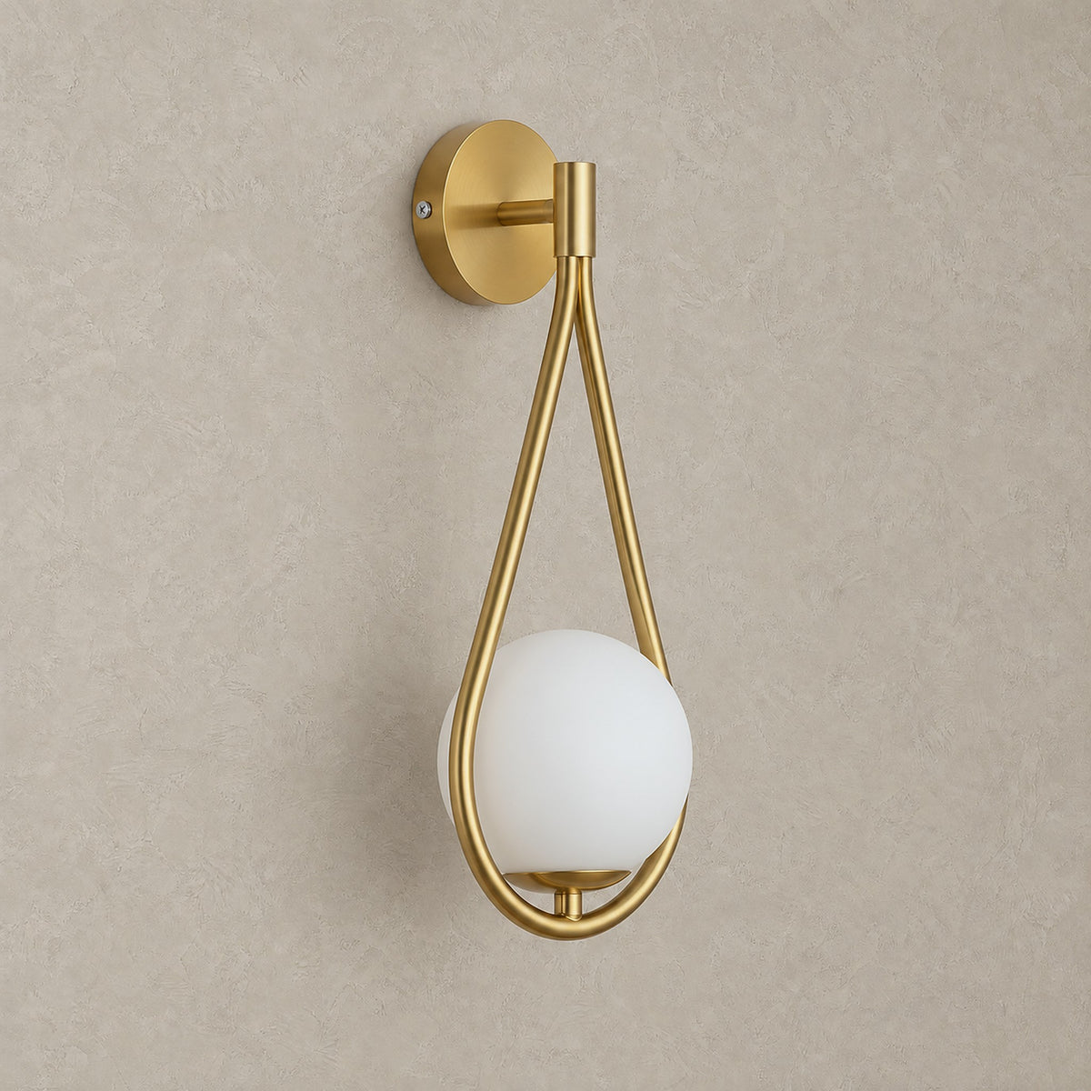 Mesaril gold plug in wall sconce, unlit, with its glass shade on a plain plaster wall