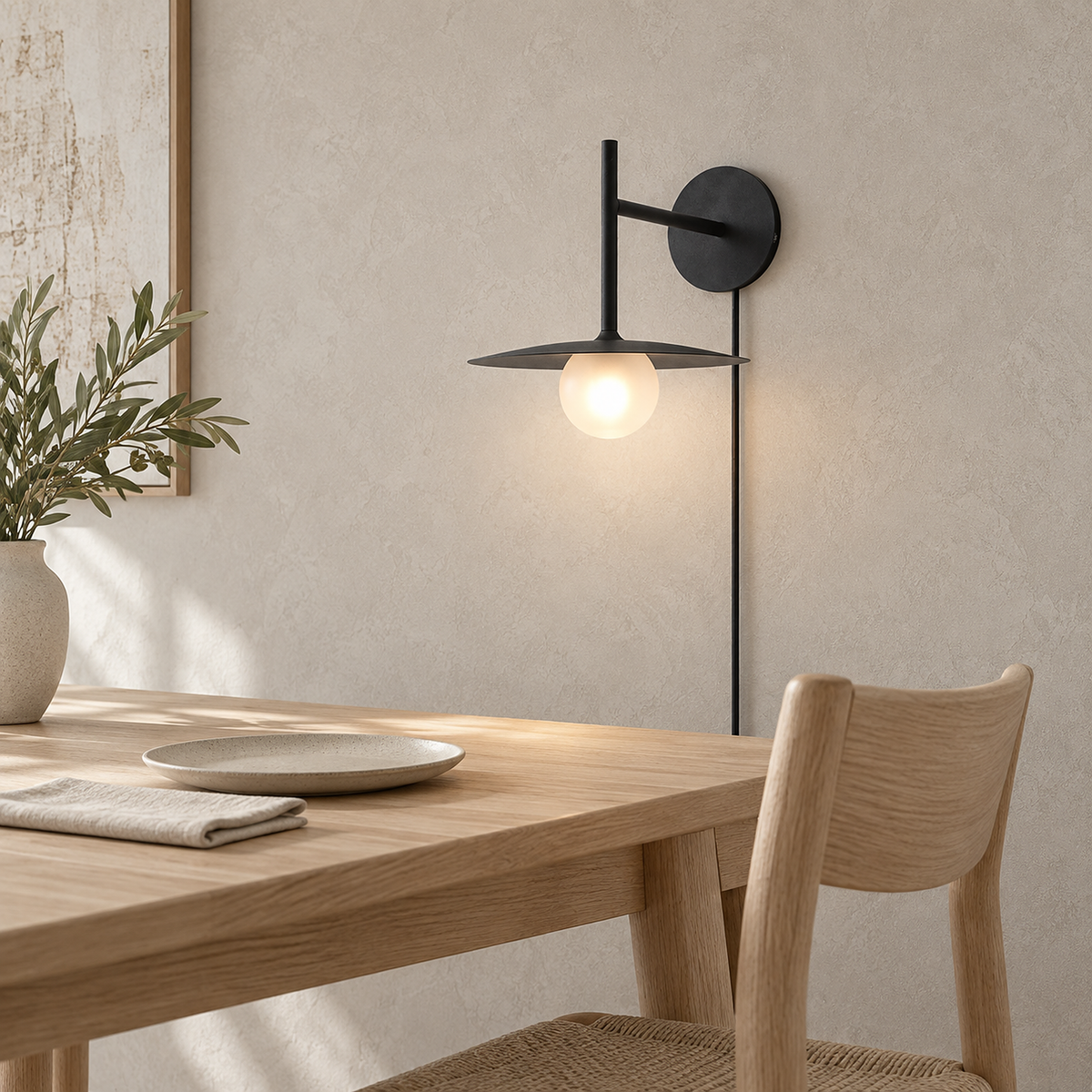 Milvaro black wall sconce glowing above a dining corner in soft daylight #color_black