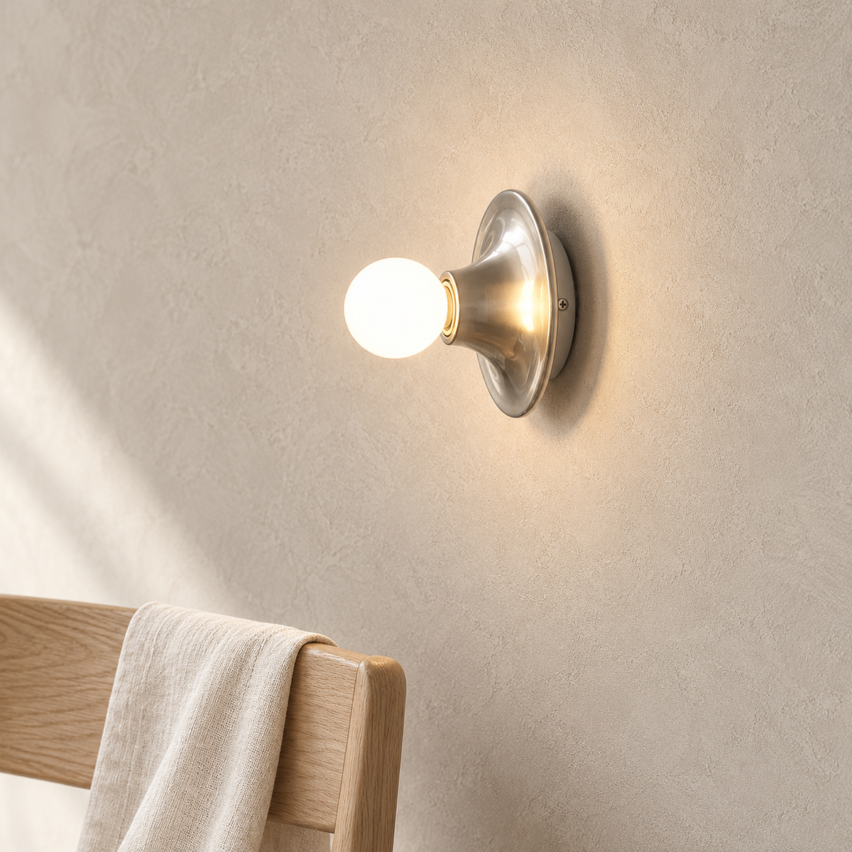 Monterla chrome wall light lit beside a dining chair corner in daylight #color_chrome
