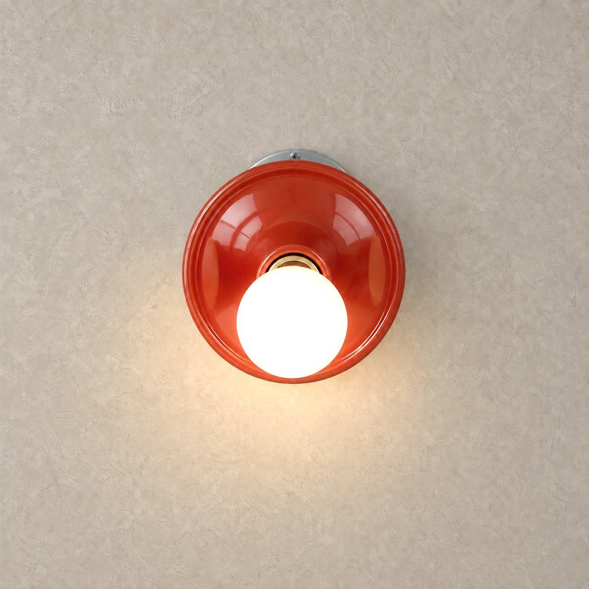 Monterla red bedside wall light lit against warm greige plaster