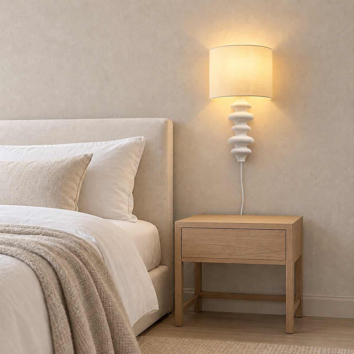 Nalimor white bedside wall light glowing beside an ivory headboard in a guest bedroom #color_white