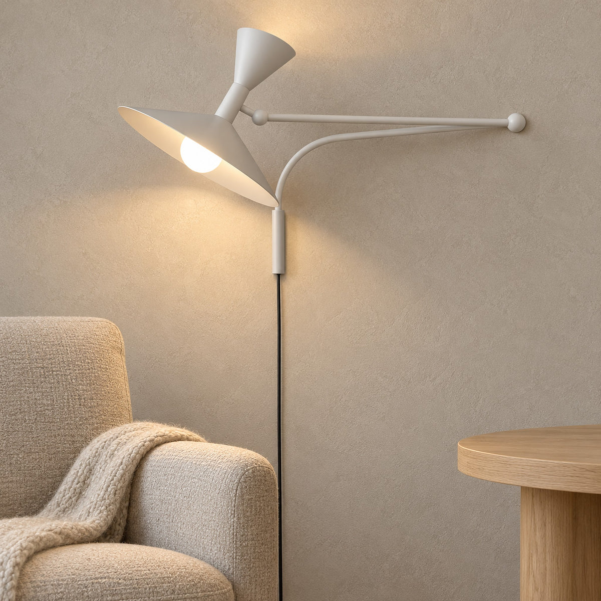Nalveto white swing arm wall lamp lit by day, reaching out over a den chair