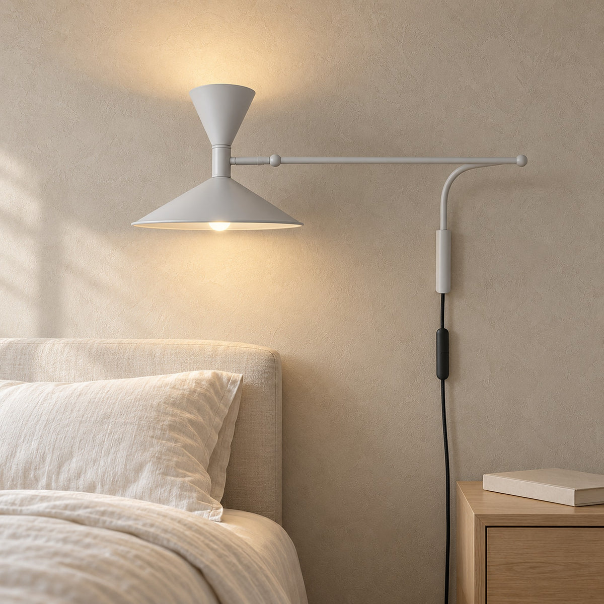 Nalveto white wall sconce lit beside a bed, showing the wall attachment in a primary bedroom by day