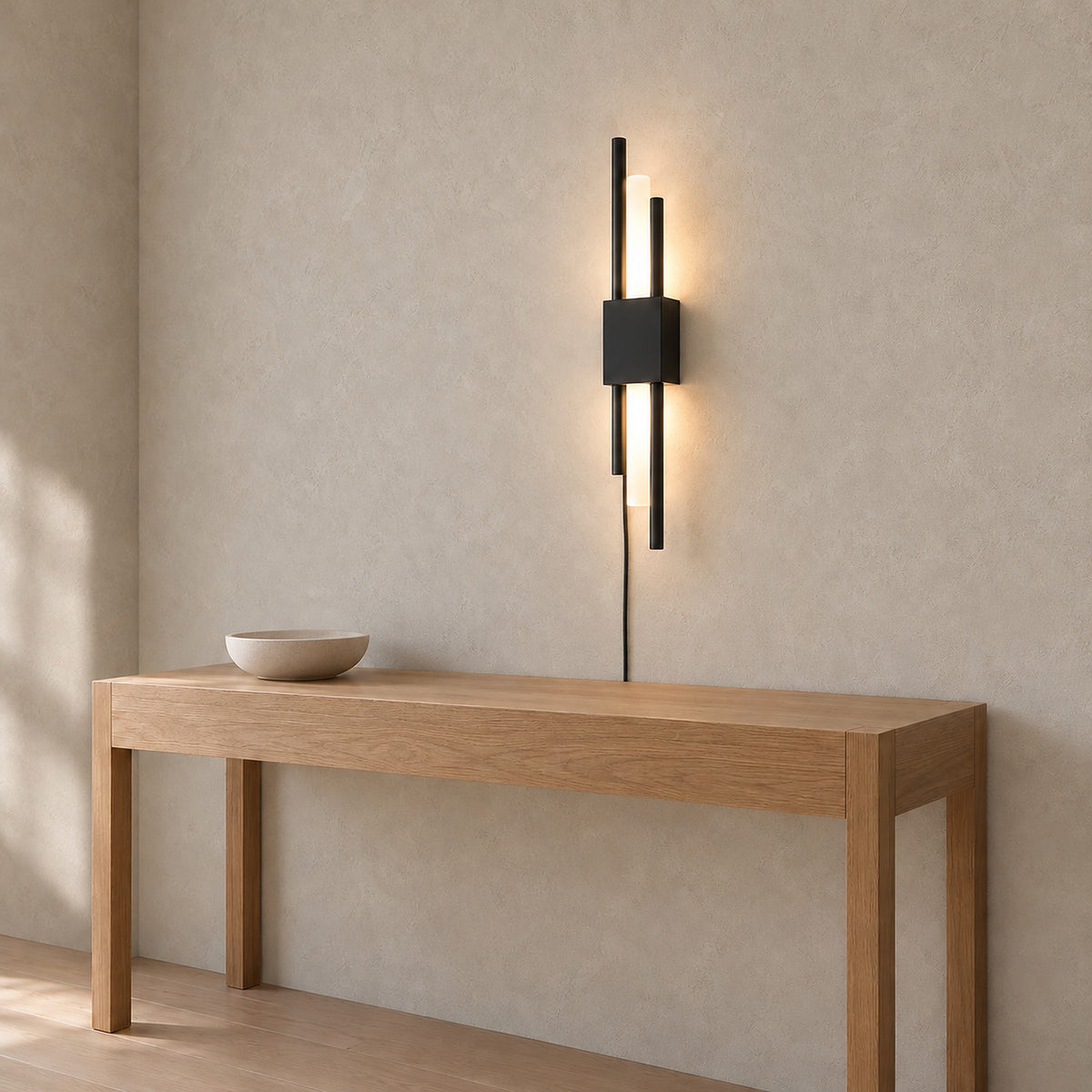 Nemirsa black LED wall sconce lit, seen in profile mounted on an entryway wall by day
