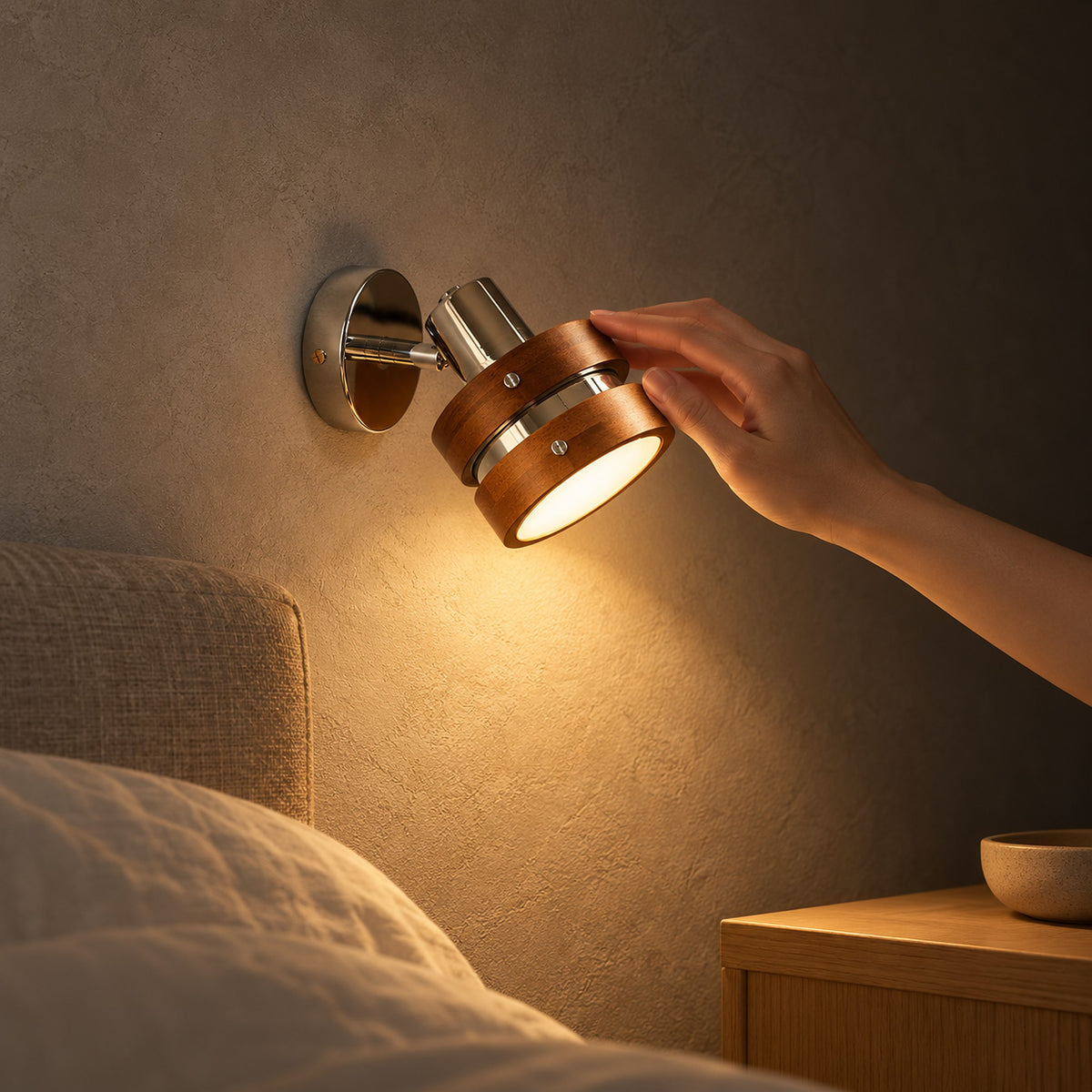 Nerilvo chrome and walnut bedside wall light glowing warm on a bedroom wall at night