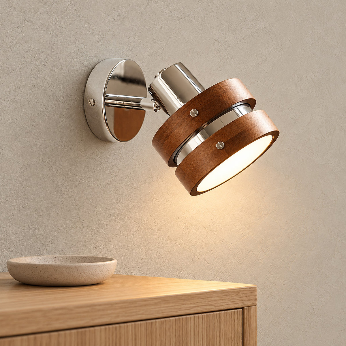 Nerilvo chrome and walnut wall light lit beside furniture in a bright dining room