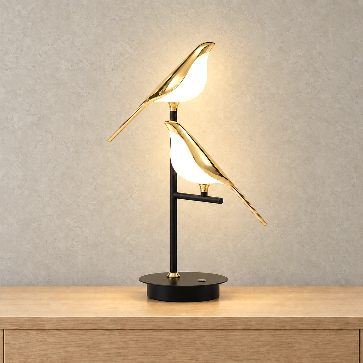 Nirelta black and gold table lamp with both birds lit from inside on a plain background