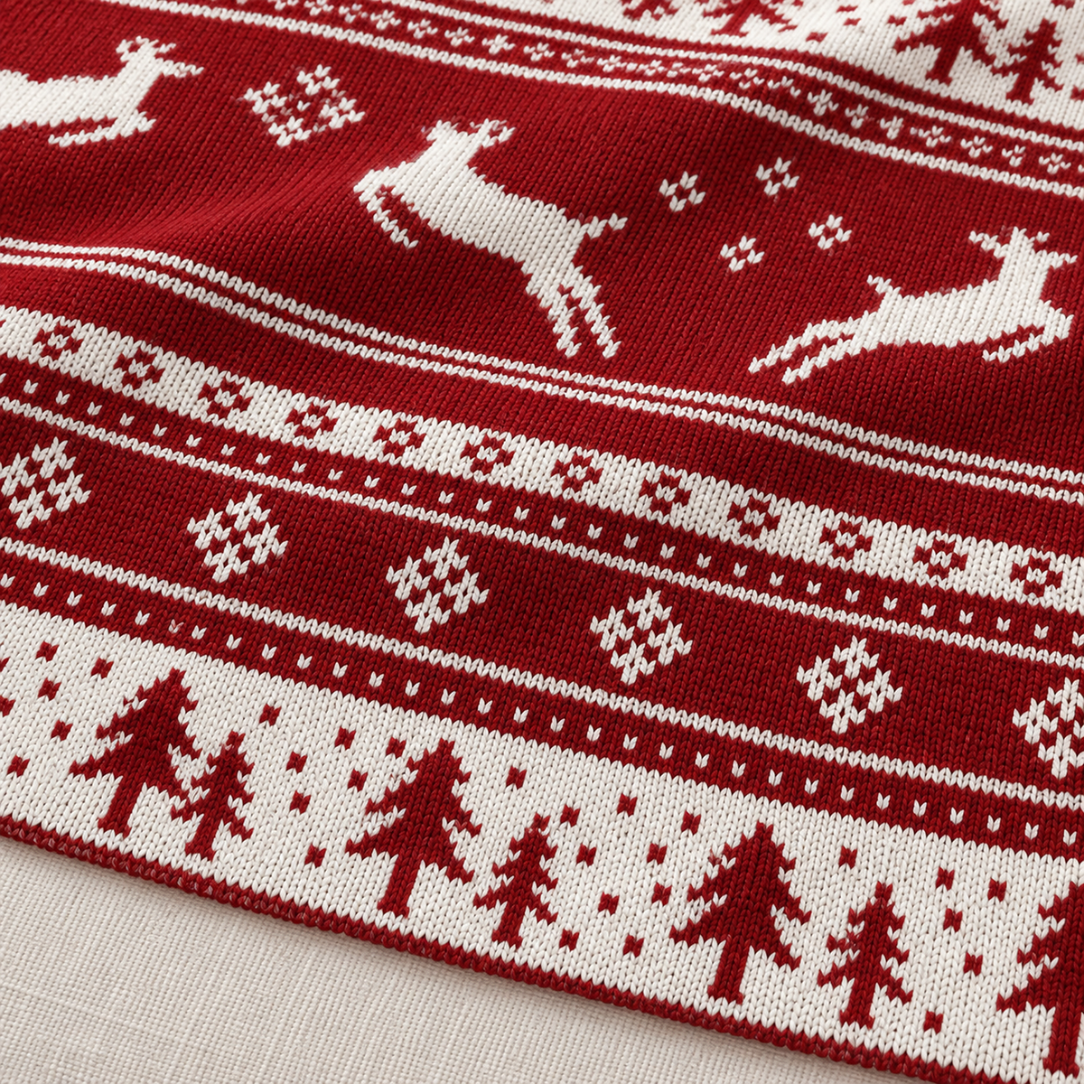 Nisarel crimson ivory knit throw blanket up close, stitches forming evergreen trees in red and white