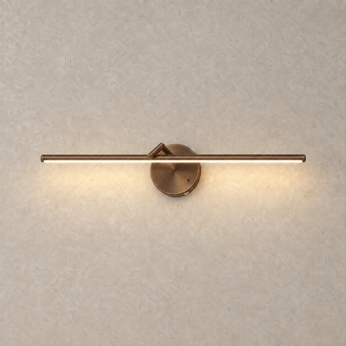 Nolesira bronze wireless wall light glowing warm against a greige plaster wall #color_bronze