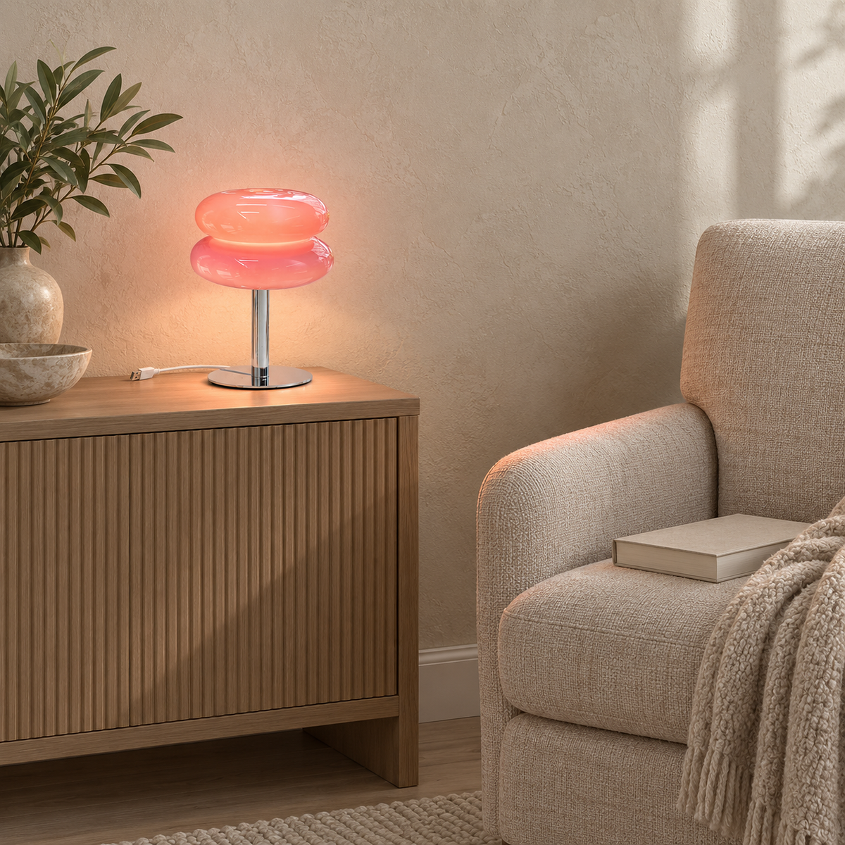Olimena glass table lamp in blush adding soft light beside a library chair #color_blush