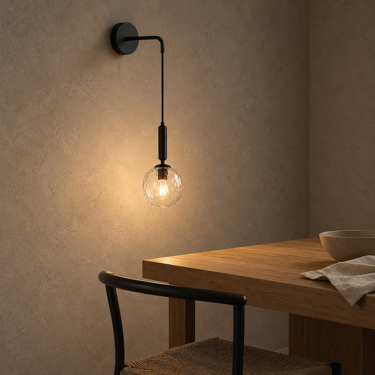 Orlamen black wall sconce glowing softly in a dining room with dark furnishings