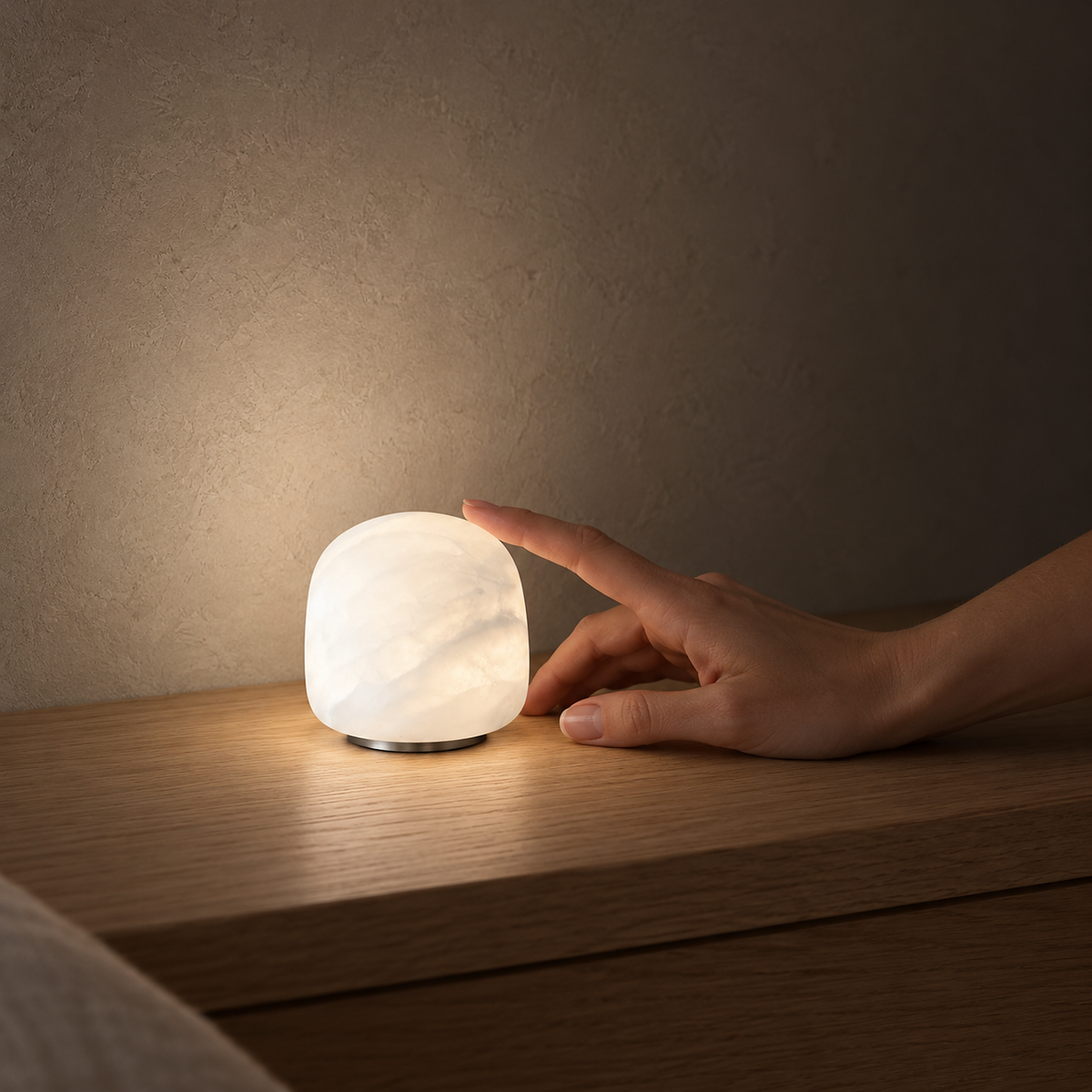 Ravelmo white bedside lamp casting a soft pool of light on a bedroom console beside a hand