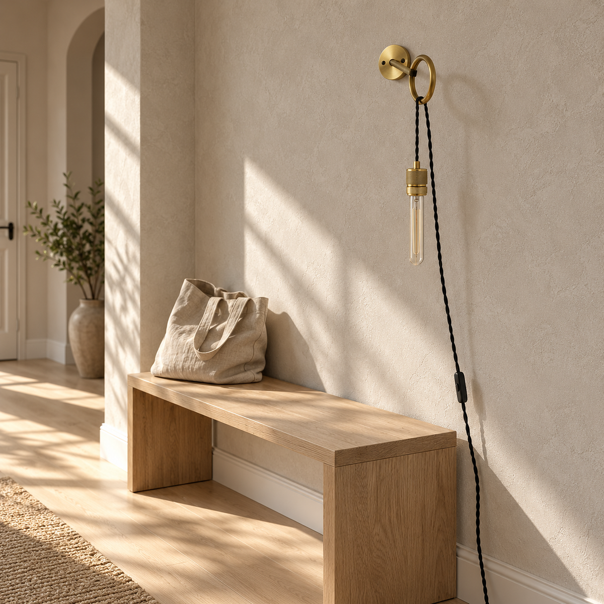 Rovenila gold wall light unlit above a bench in a bright daylit entry foyer