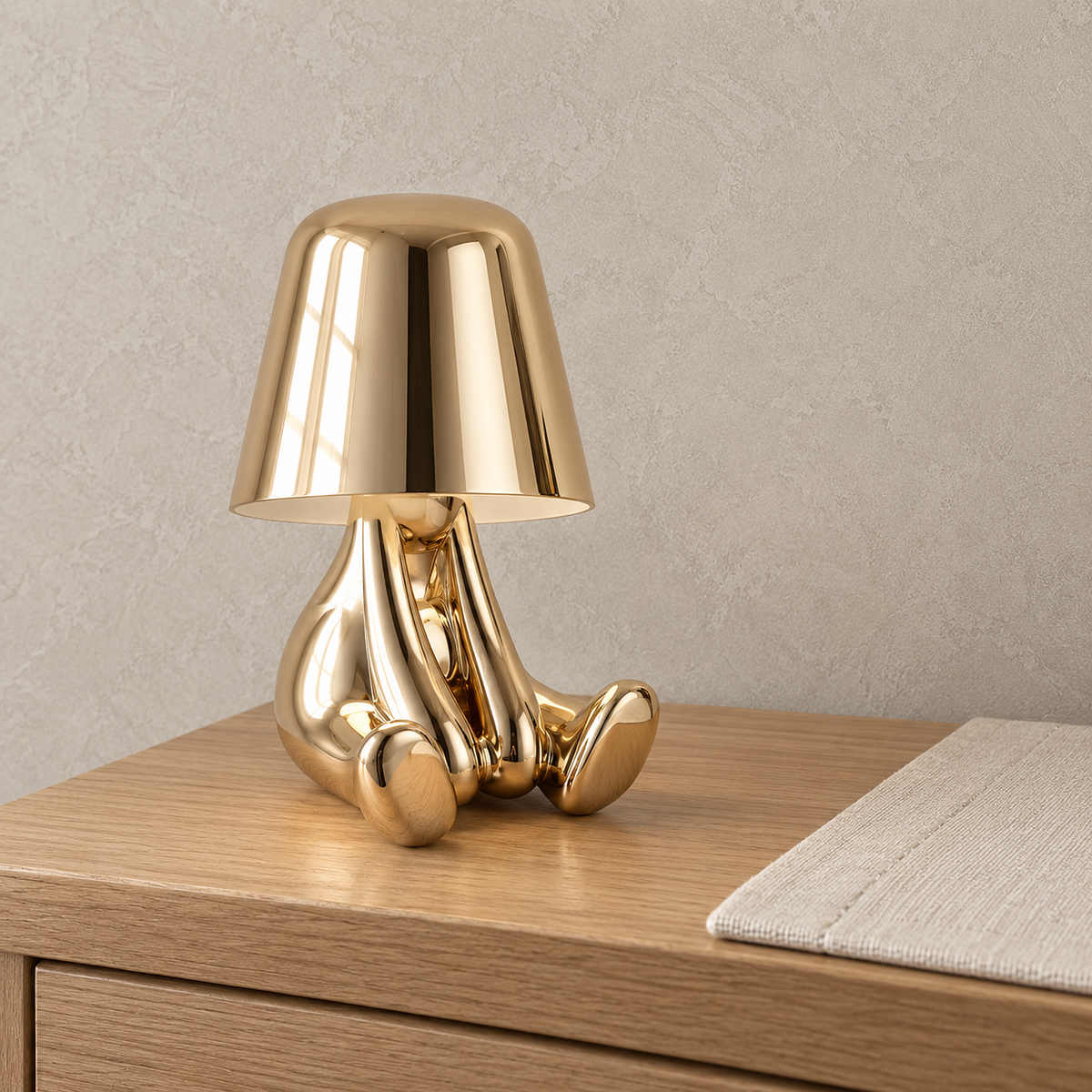 Sarovel gold table lamp in close detail, showing the shiny shade and seated figure in a dressing room