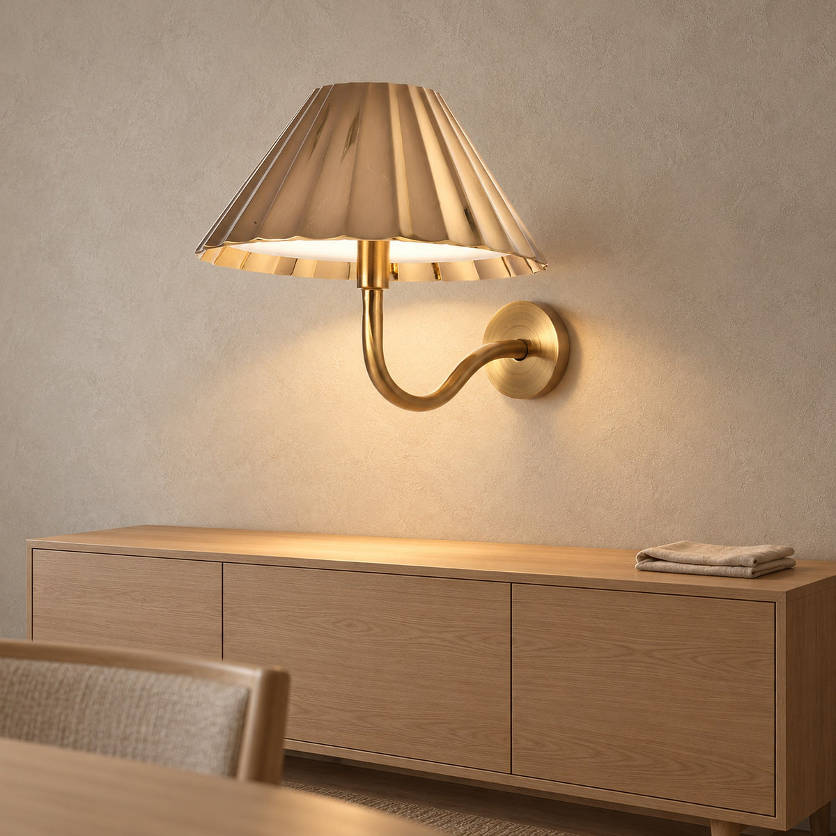 Selorna gold cordless wall lamp lit above a clear dining room sideboard
