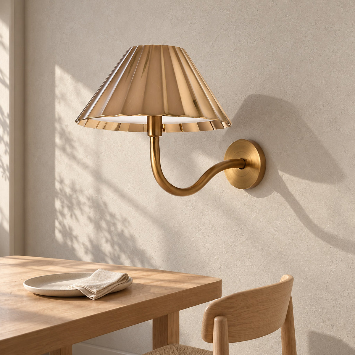 Selorna gold wall light unlit and mounted above a sunlit dining table