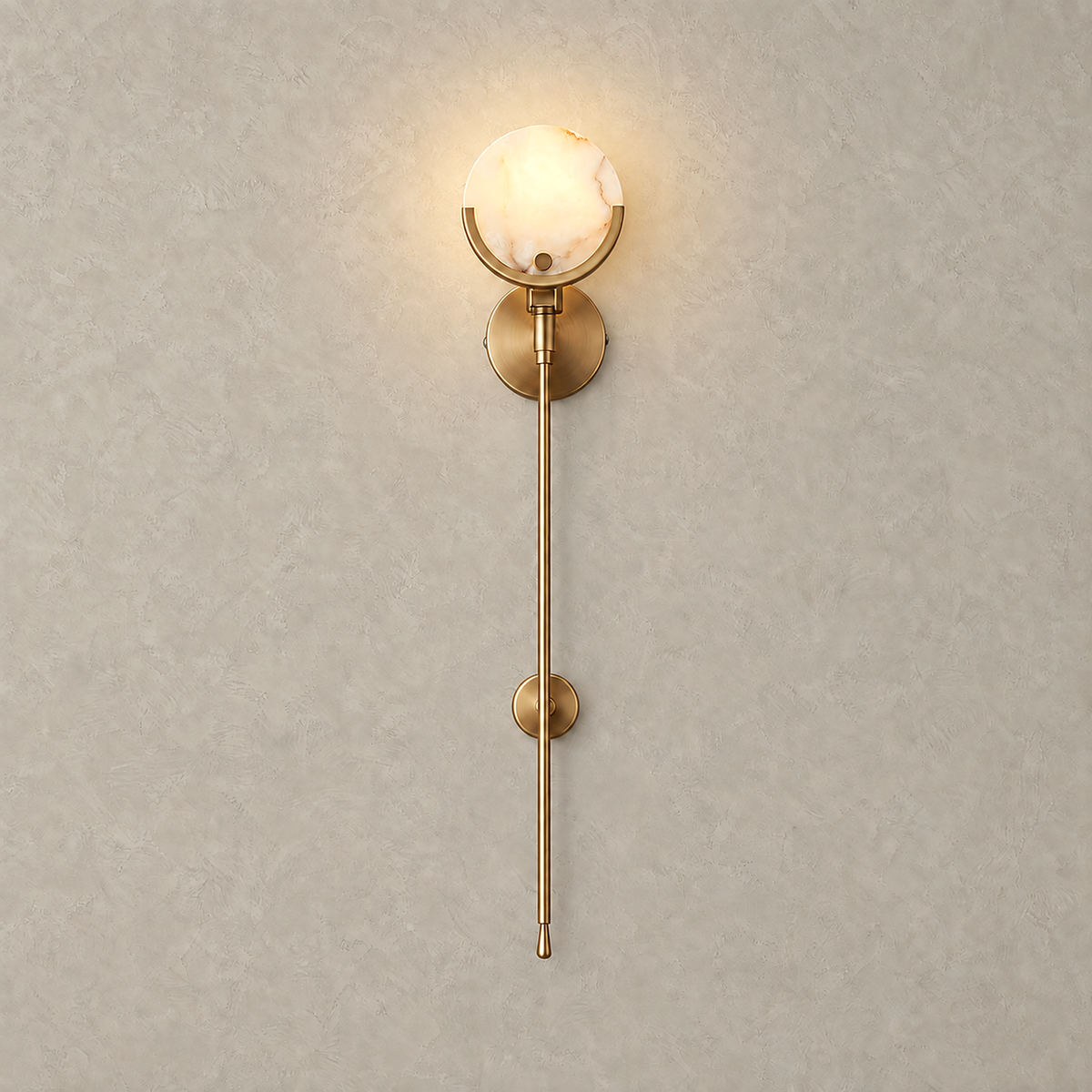 Serrinte brass wall sconce lit on a plain plate, glowing pale stone disc on a slim brass stem