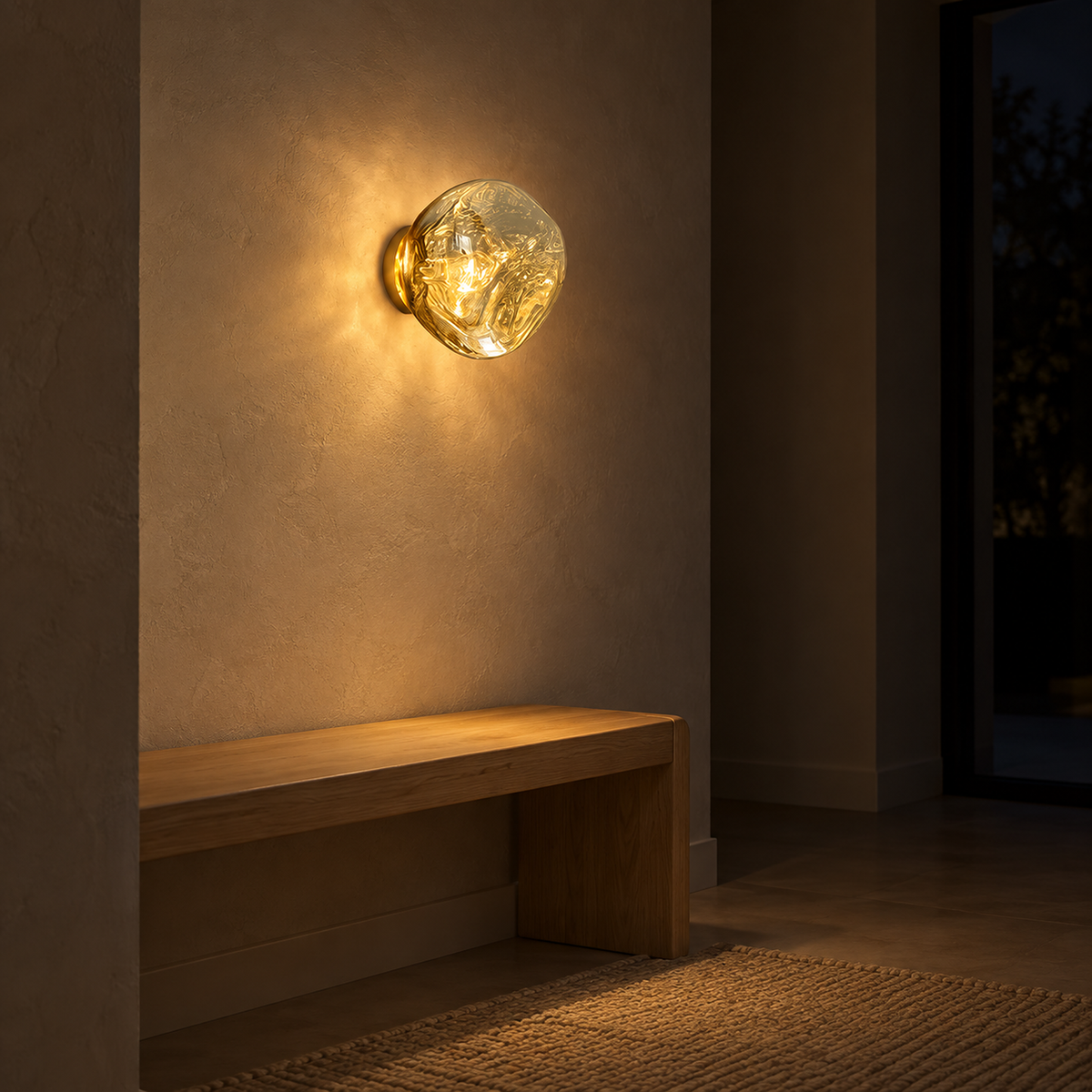 Sevalira gold wall light casting warm white glow above an entry bench at night #color_gold