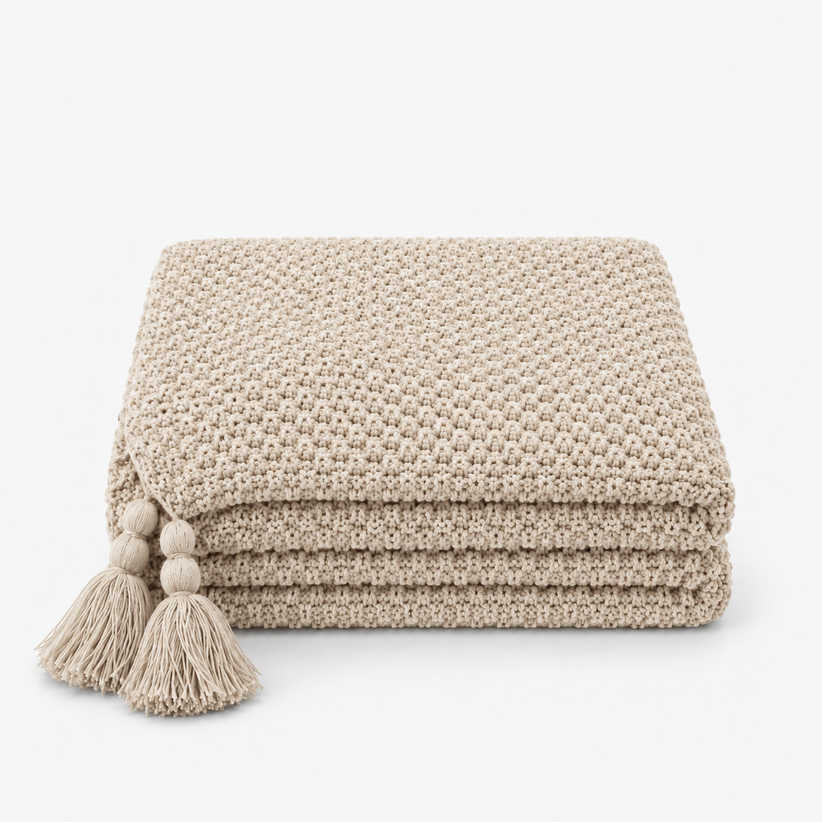 Soralvi beige knit throw blanket folded with matching tassels at the corners #color_beige