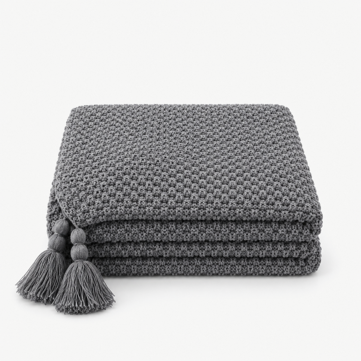 Soralvi knit throw blanket in gray, loosely folded with tassels at the corners