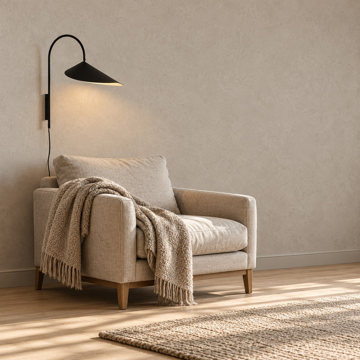 Talirsa black plug in wall lamp with its cord, lit beside a living room armchair