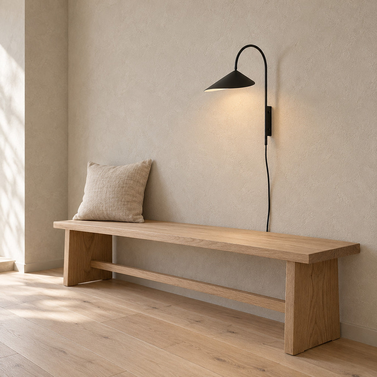 Talirsa black wall light arching over a dining bench in a daylit dining nook