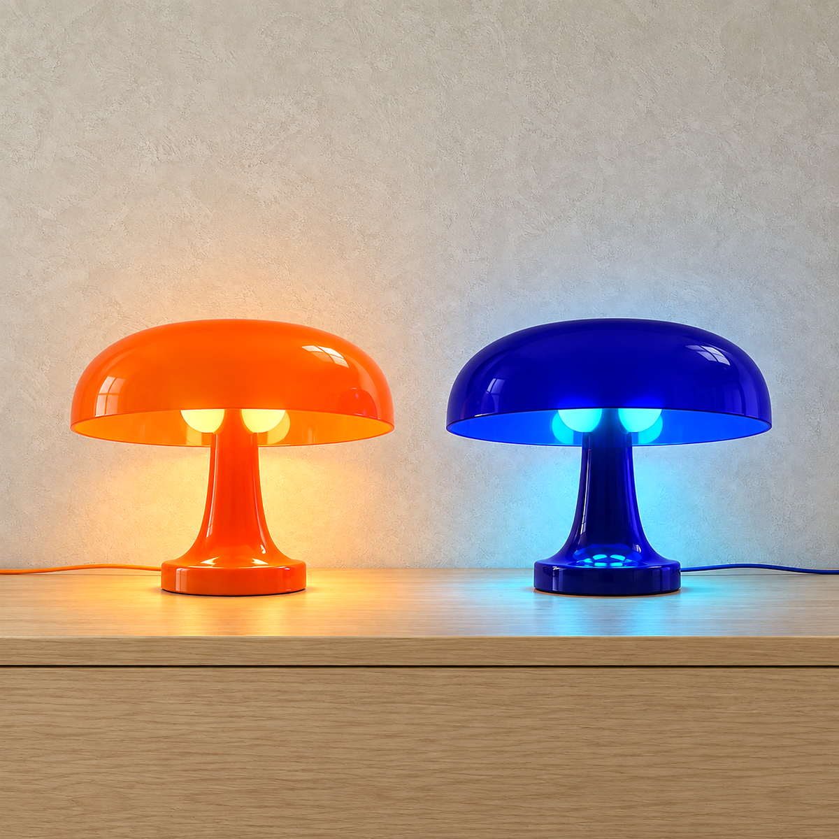 Tamolise table lamps in orange and blue, both lit side by side on a studio plate